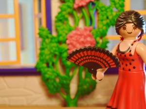A figurine of a woman in a red dress holding a fan.